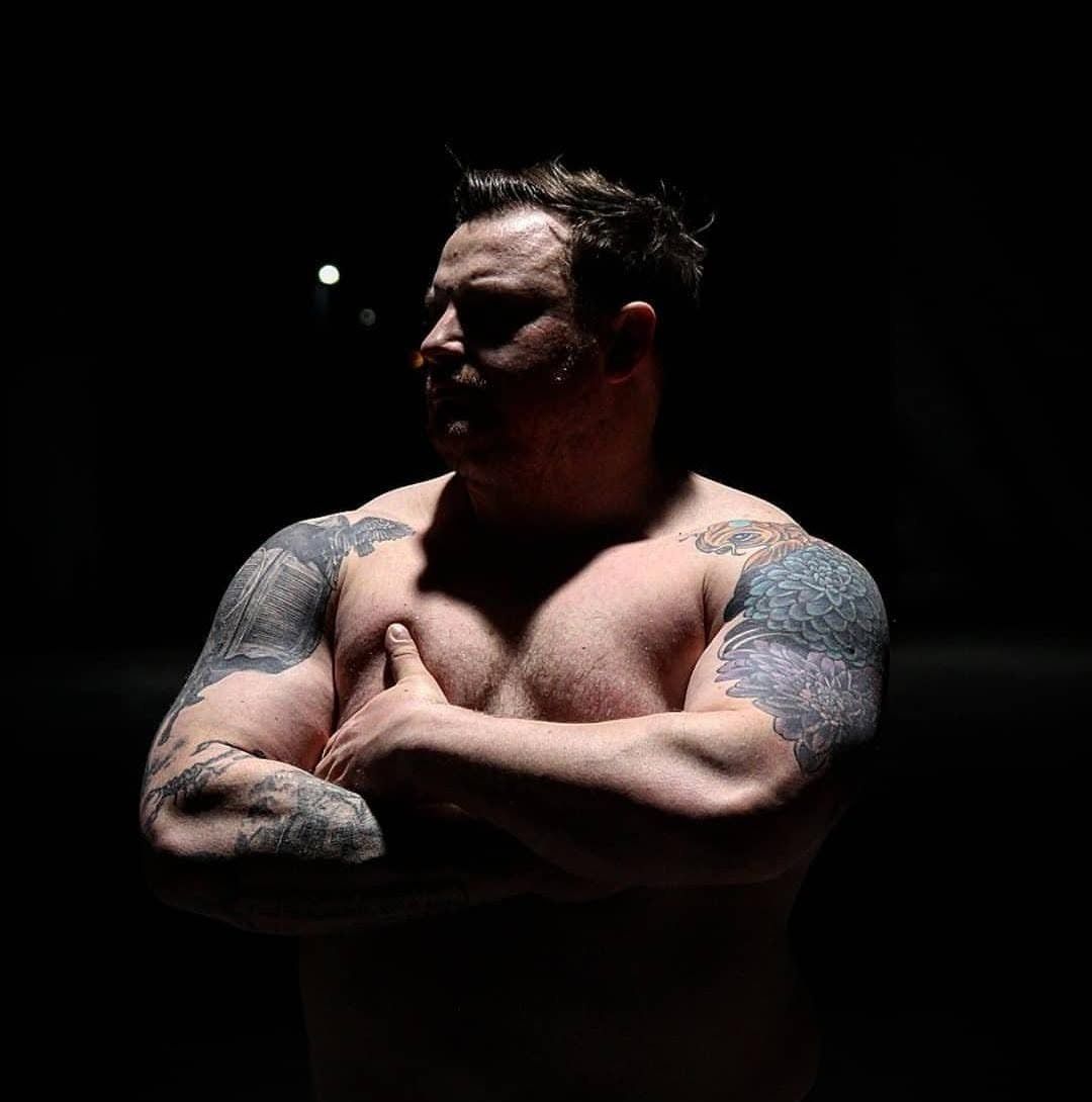 Portrait of Vinny Jones, arms folded, lit from the side